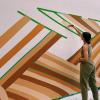 Maddie Sanders paints a wall with lines in various shades of brown