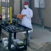 PhD student in a lab coat and mask outside gathering air samples