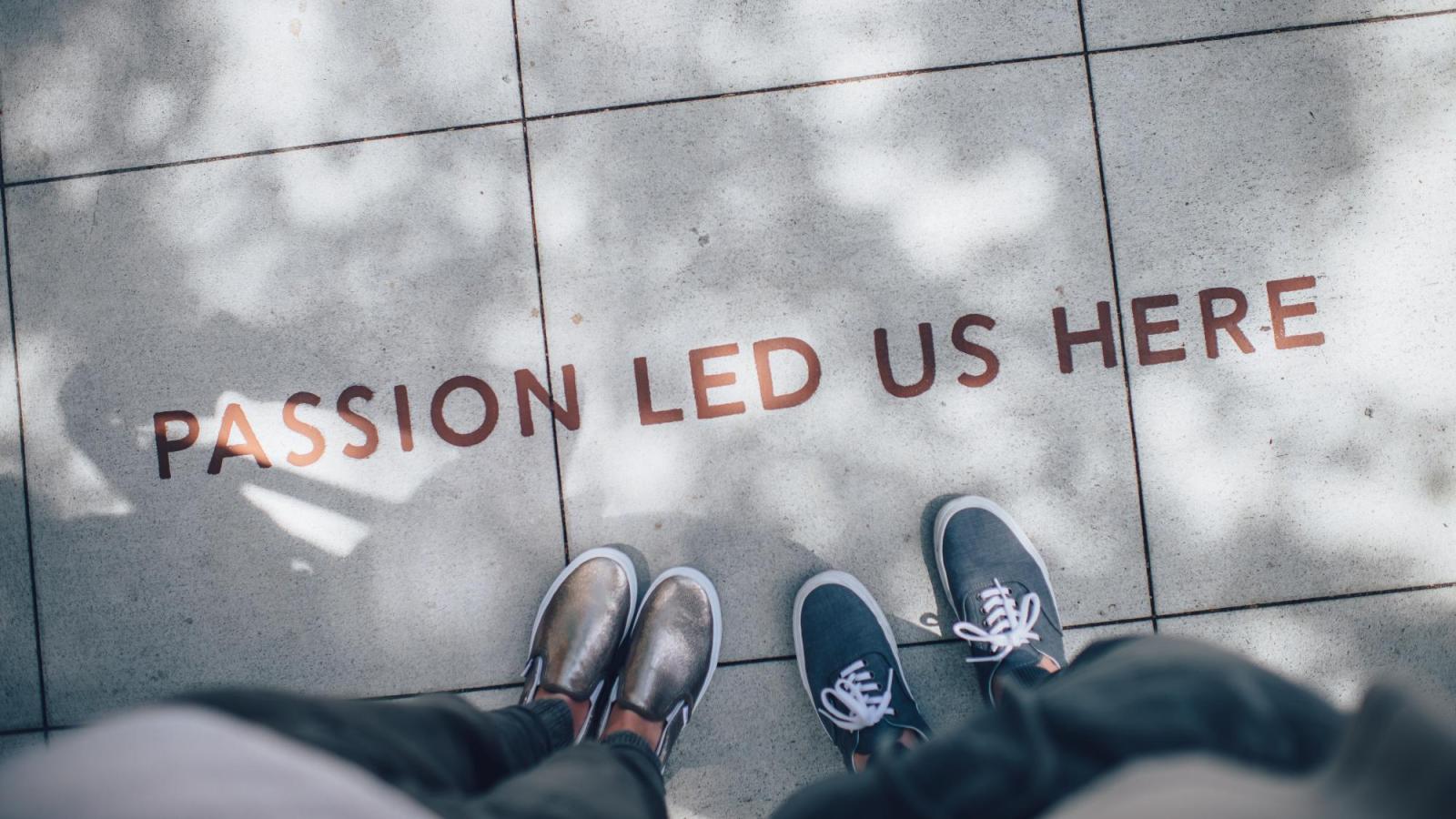 sidewalk message says passion led us here with two people's shoes in the frame.