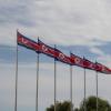 several north korean flags on flag poles with sky in background