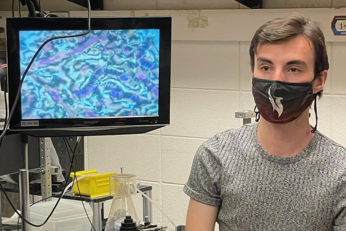 Male student stands next to computer