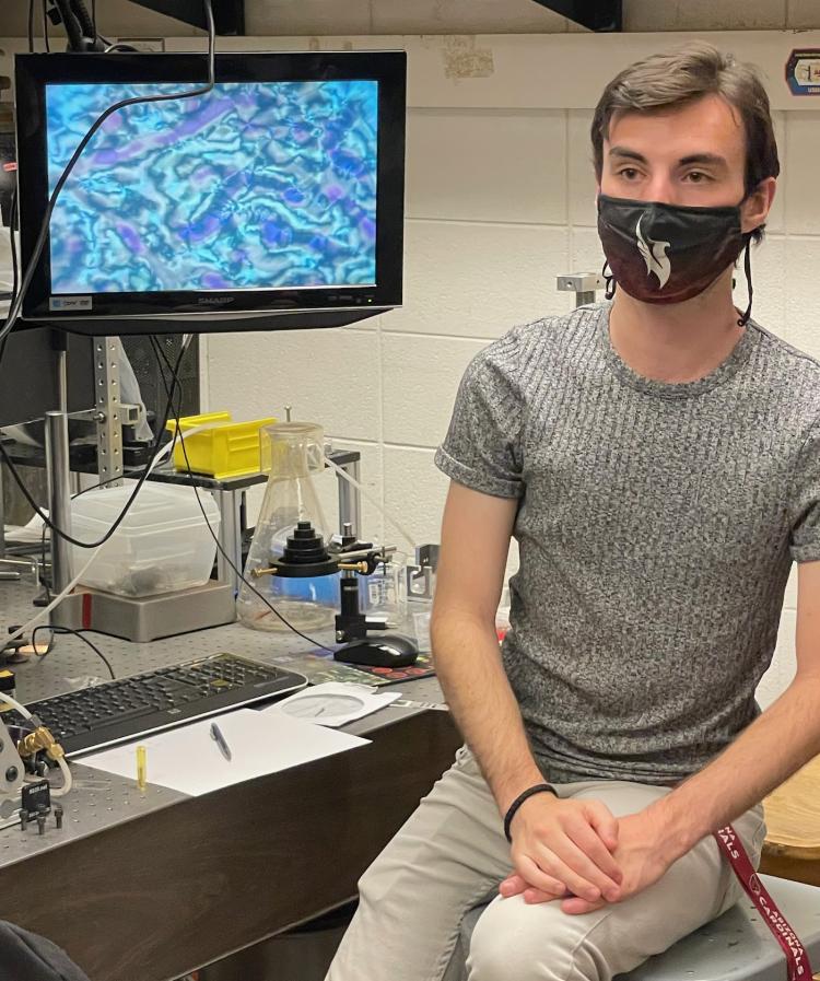 Keith Hedlund stands in front of microscopic image