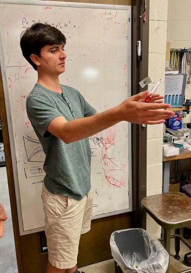 Roei explaining his science in front of a whiteboard