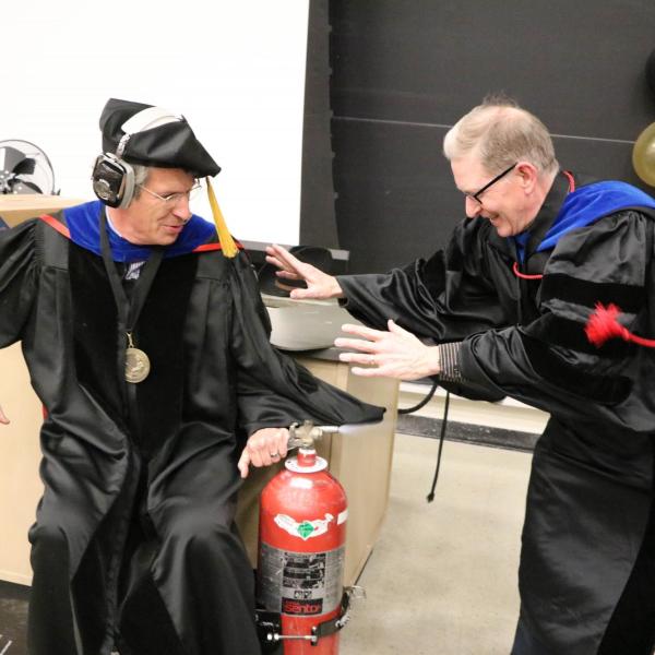 Professor Paul Beale performing demonstration on a wheeled cart with two fire extinguishers on either side.