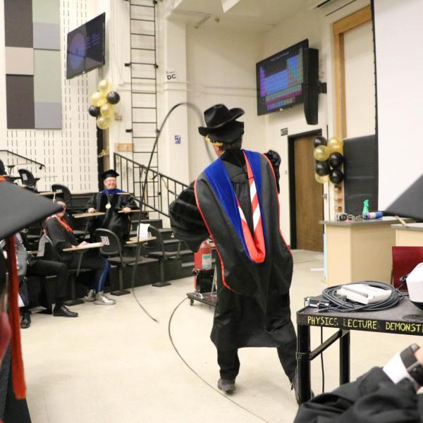 Professor Paul Beale performing demonstration in a cowboy hat with a whip.