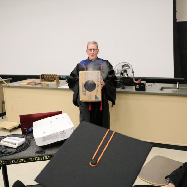 Professor Mike Dubson performing physics demonstration by blowing smoke rings from a cardboard box.