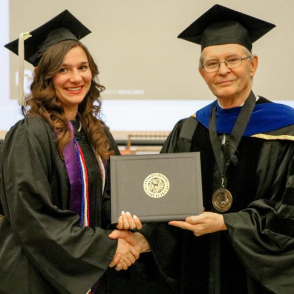 Undergraduate Katerina Overburg receiving diploma cover.