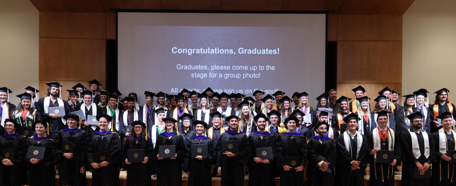 Group photo of graduating physics students in cap and gown