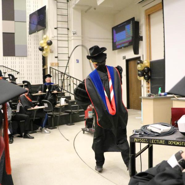 Professor Paul Beale performing demonstration in a cowboy hat with a whip.