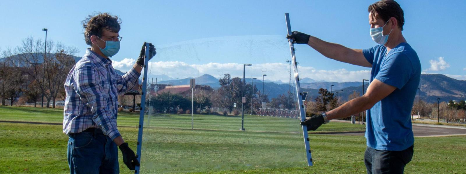 Researchers holding a transparent film in front of the mountains