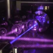 A blue laser beam excites a cube-shaped cloud of strontium atoms. 