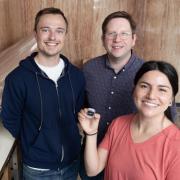 Alexander Staron, William McGehee, and Gabriela Martinez pictured with the chip-scale atomic beam clock.