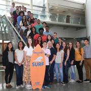 NIST SURF students pose for a photo next to a surf board