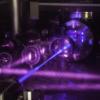 A blue laser beam excites a cube-shaped cloud of strontium atoms. 