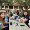 10 students sitting at two picnic tables talking
