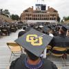 A student wearing a graduation cap with the CU interlocking logo decorated on top