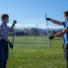 Two researchers holding a transparent film in front of the rocky mountain range