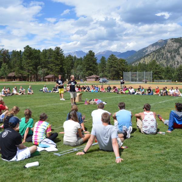 Orientation attendees gather on the activity fields at the YMCA camp of the Rockies for a group challenge