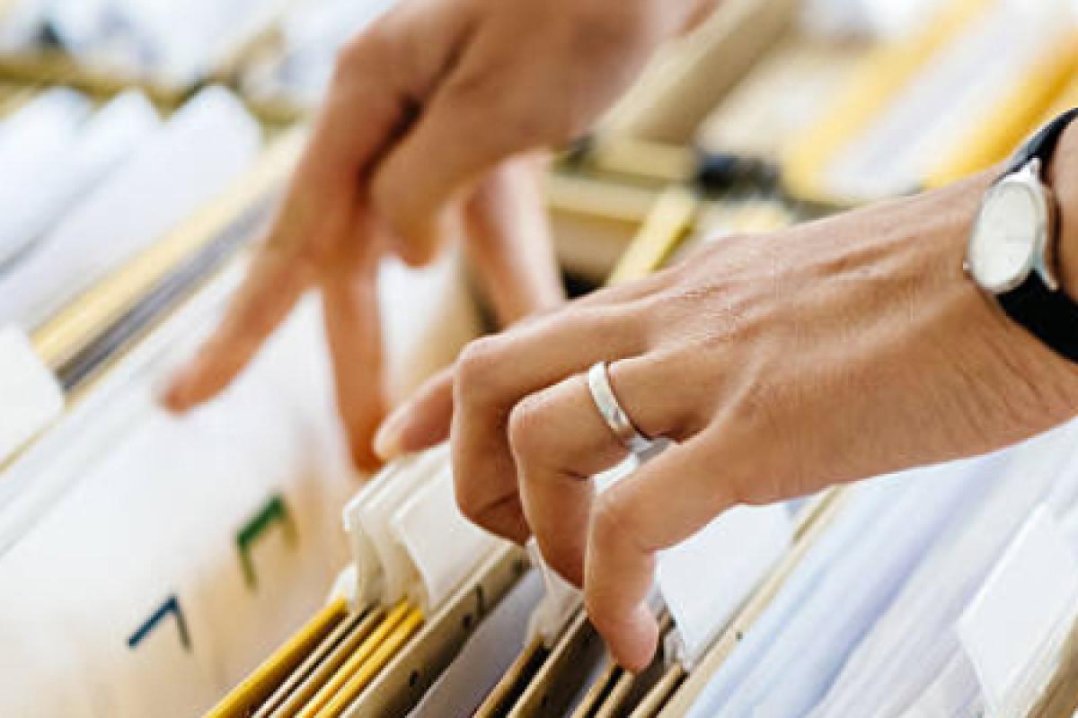 A person pulling a file out of a filing cabinet