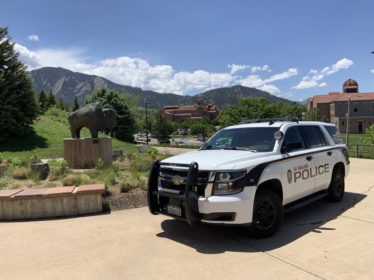 Police car on campus with Flatirons and buffalo statue