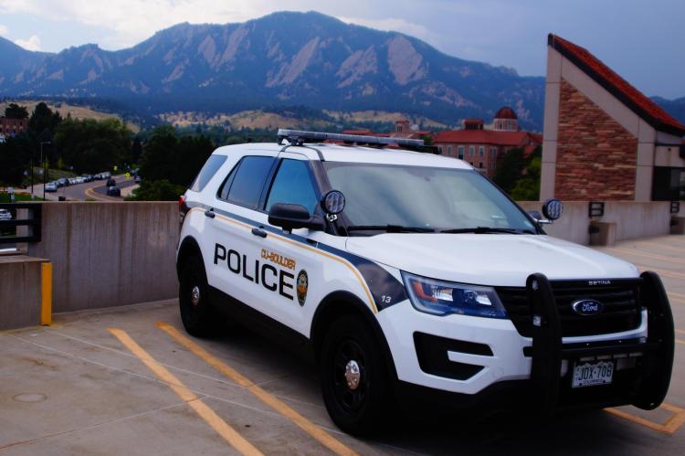 A CUPD patrol car parked on campus with the Flatirons in the background