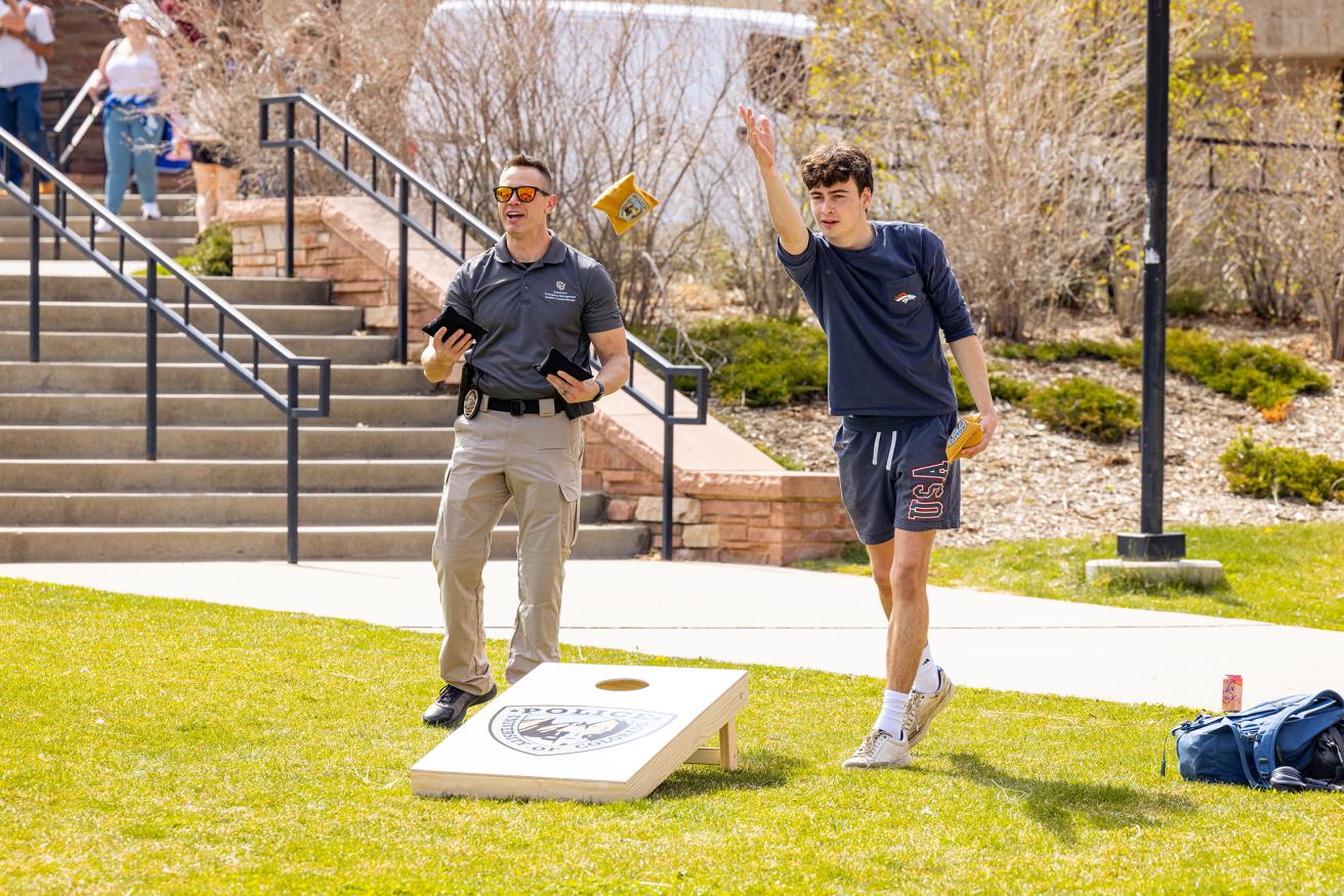 Officer playing corn hole with student at SAAM event