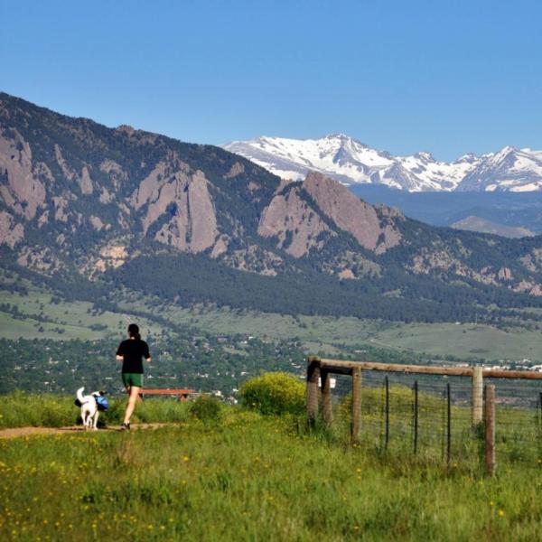 Student running with dog along trail outside of Boulder