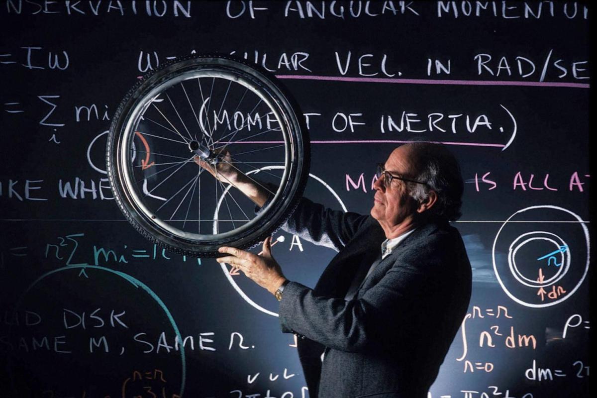 person with a bicycle wheel in front of a chalkboard