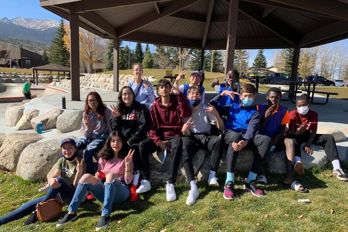 a group of students sitting on boulders in front of a park pavilion