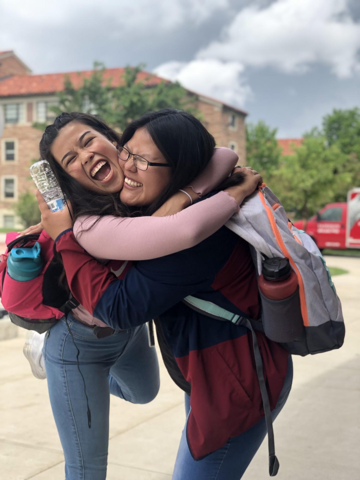 two CUUB students smiling and hugging each other