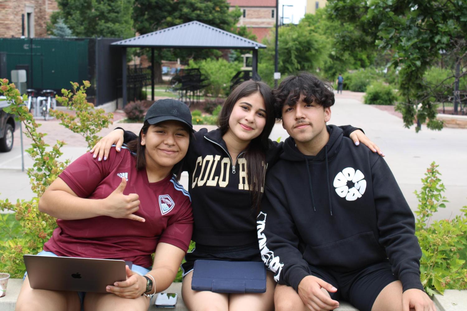 three students sitting together on campus