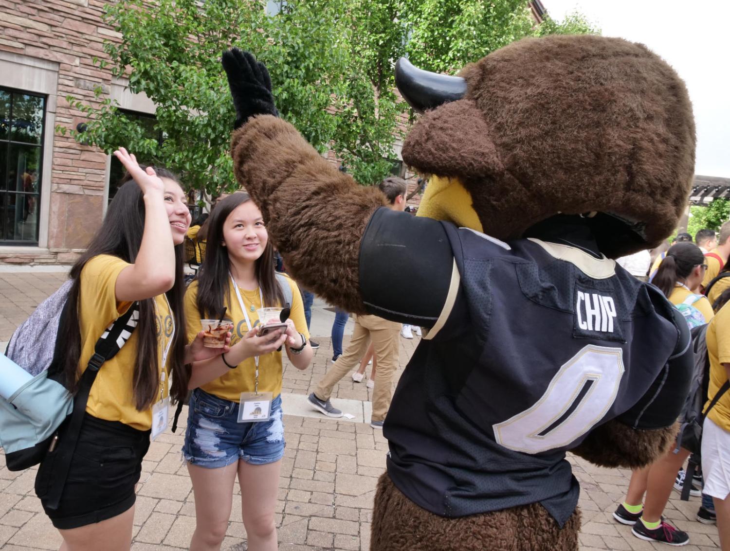 students give the mascot Chip the Buffalo a high-five during a social event