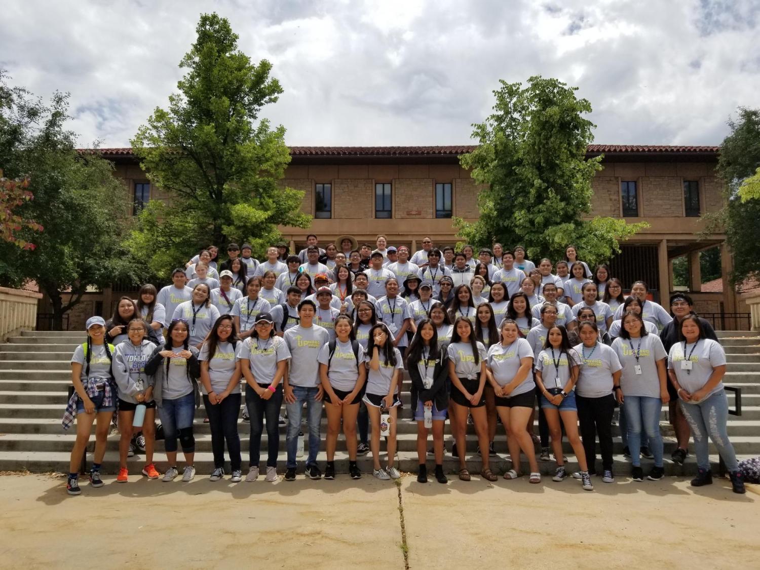 a group of students pose for a photo on some steps on campus during the summer academic institute