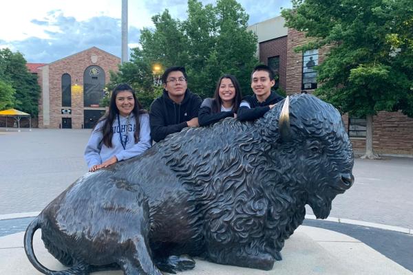 4 CUUB students posing behind the Ralphie statue in front of Folsom field