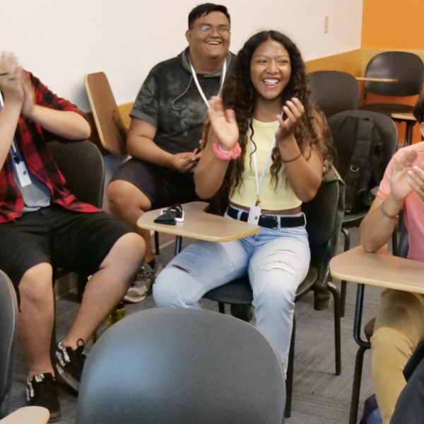 a group of PCDP students sitting in a classroom clapping for a presentation