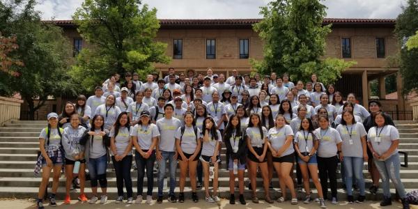 a group of students pose for a photo on some steps on campus during the summer academic institute