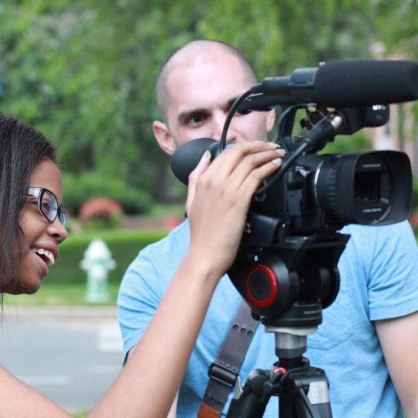 Professor Gino Canella helping Jacqueline Lee with video camera during Broadcast I session