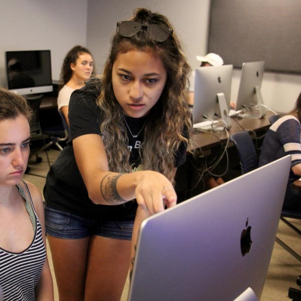 Aabriti Shrestha helps Emma Baziuk set up her project during a critical media practices class.