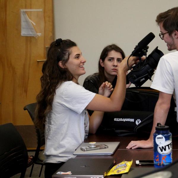 Kate Robinson points a camera in Nic Lawrence's face.