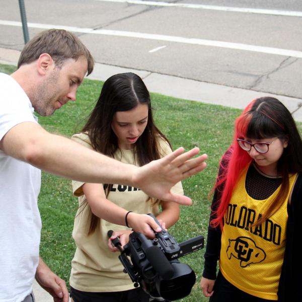 Pat Clark helps Lauren Irwin and Alondra Carlos-Ferrales find a better angle for their shot.