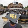 A student wearing a graduation cap with the CU interlocking logo decorated on top