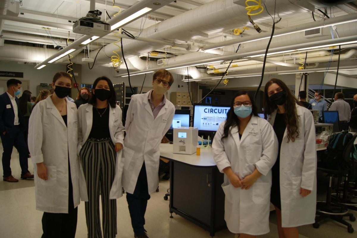 Doctor Delivery team stand in white labcoats with their project