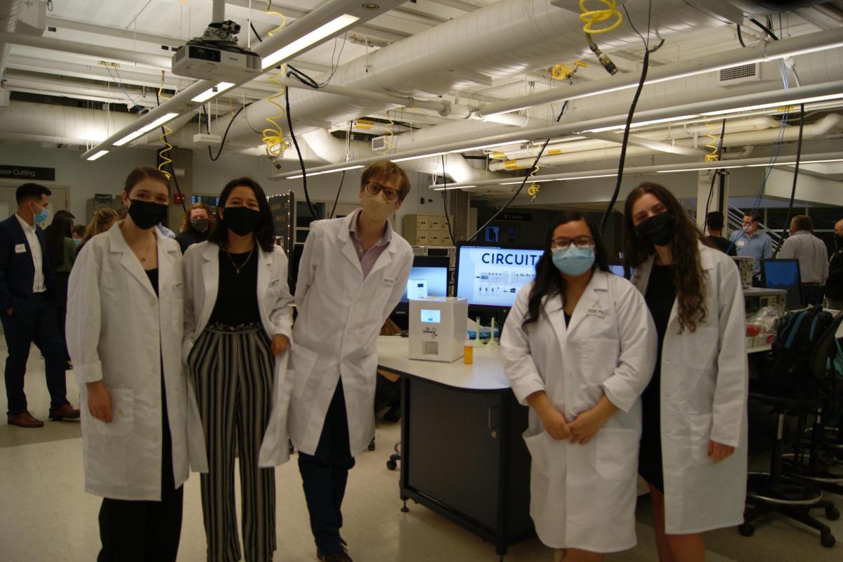 Team in white lab coats with pill dispensing machine