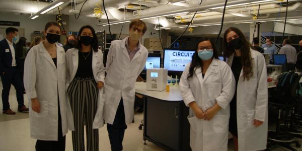 Team in white lab coats with pill dispensing machine