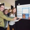 four students gesture at a research poster with the title Basketball or Swimming