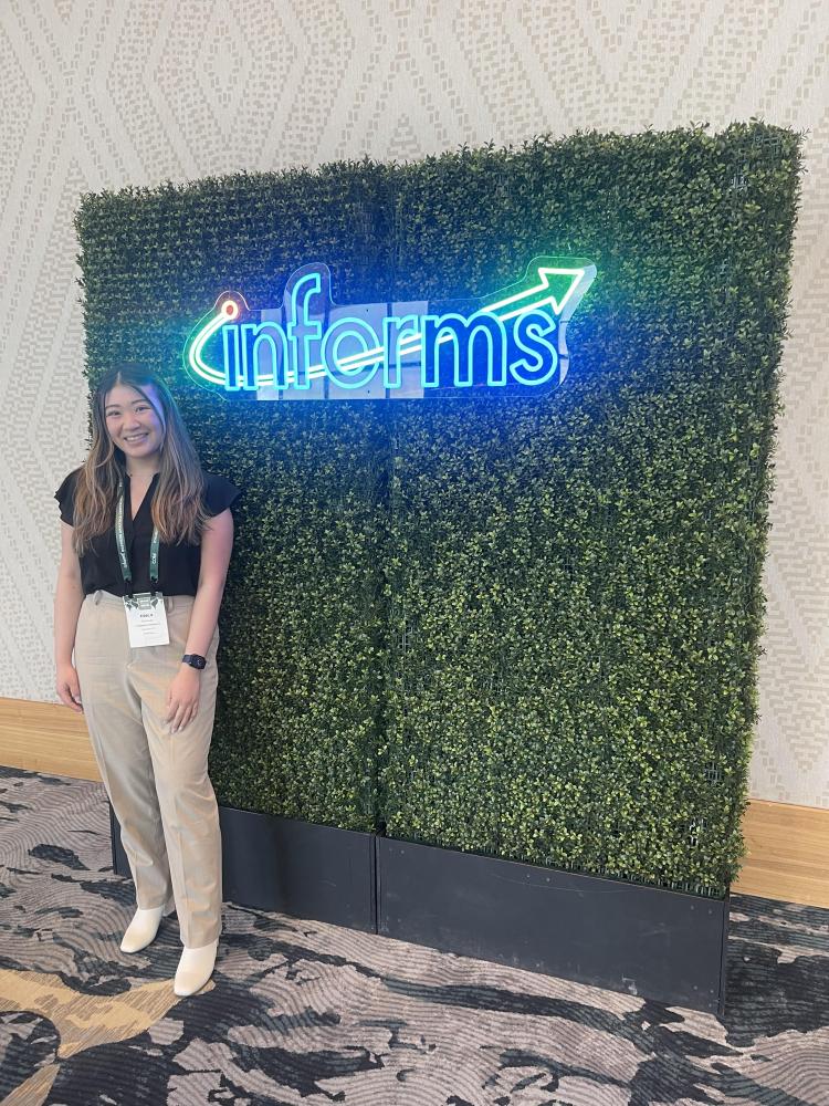 Erica standing in front of a green wall with informs written on it