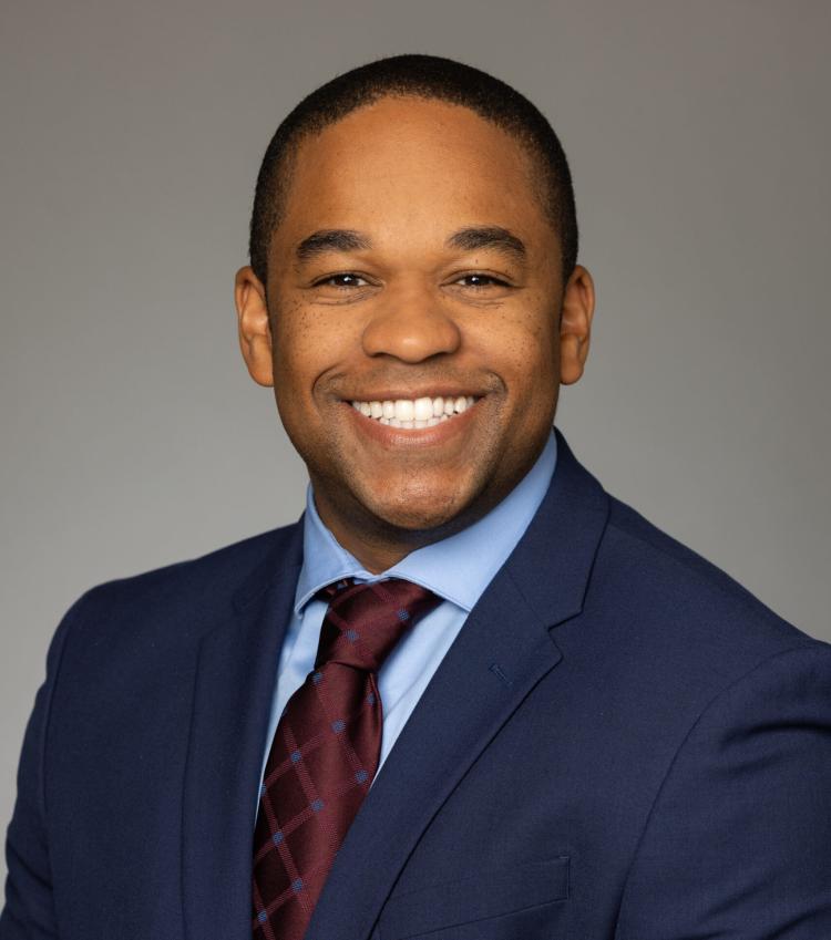 A headshot of Floyd wearing a suit and tie