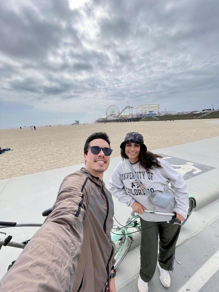 Melody and another person standing infront of a beach holding bikes