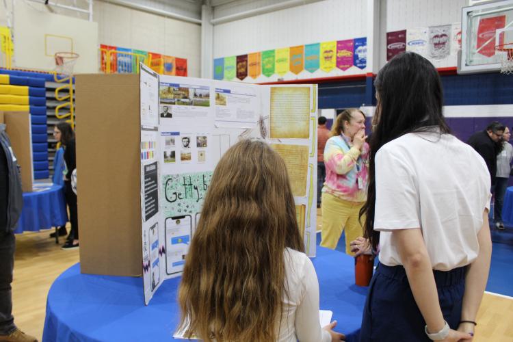 Cassandra standing with a student looking at a poster