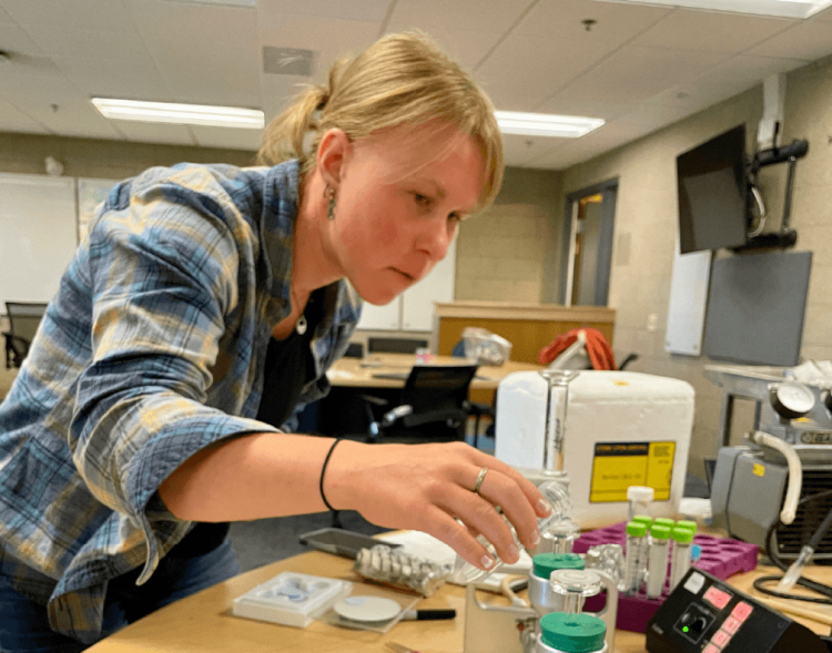 Katie Ryan reaching over a table full of science equipment
